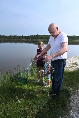 As his grandchildren look on, this gentleman empties a crab from a box trap at the Heislerville impoundments. Photo: J. Morton Galetto