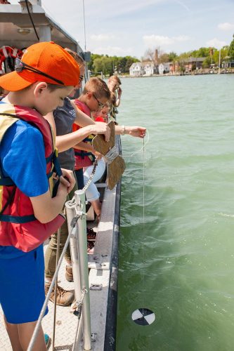 Students lower Secchi disk to check water clarity/turbidity. Photo: Ohio Sea Grant program